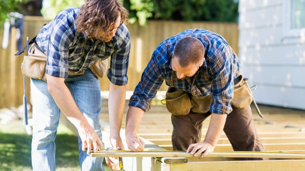 Two contractors working together to install a deck for a house